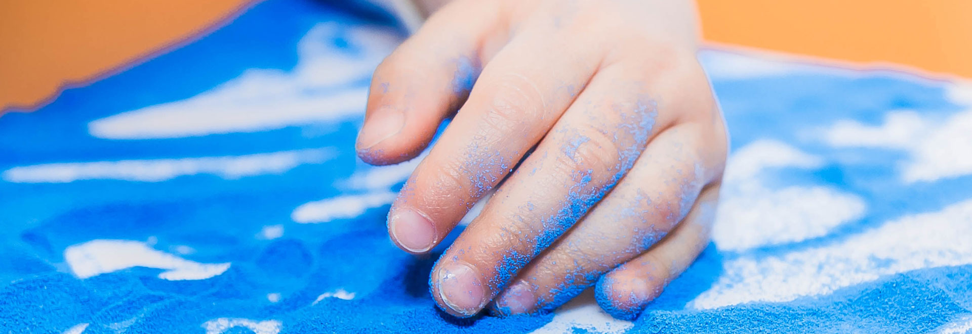 Ergotherapie Gute - Hand in blauem Sand